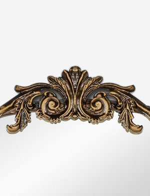 Detailed view of the traditional scroll detailing on the top of the Tulca arched gold mirror with flat bottom edge.