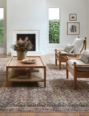 Billie Rug in ink and salmon by Amber Lewis x Loloi lays under two wooden-framed accent chairs and a rectangular coffee table