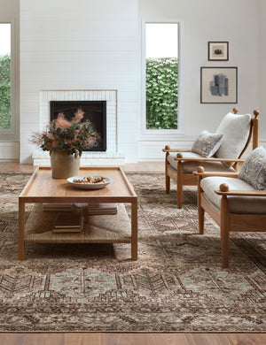 Billie Rug in clay and sage by Amber Lewis x Loloi lays under two wooden-framed accent chairs and a rectangular coffee table