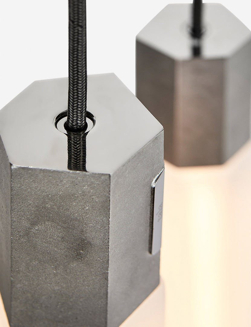 #color::stainless-steel | Close-up of the sand casted stainless steel hardware on the Basalt slender hexagonal 3-light pendant light by tala