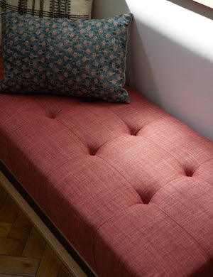 The Tamra blue and pink lumbar pillow with floral patterns sits on a red linen bench