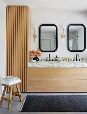 The Heritage indigo rug in its runner size lays in a bathroom with his and hers sinks, wooden cabinetry, and two mirrors
