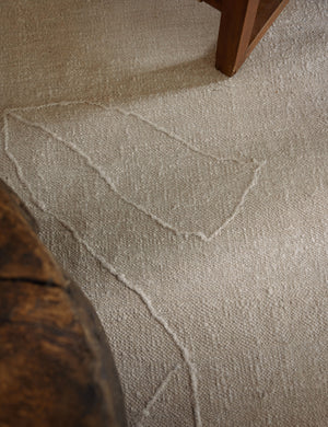 Close up of the beachwood rug under a wooden coffee table and wooden framed accent chair