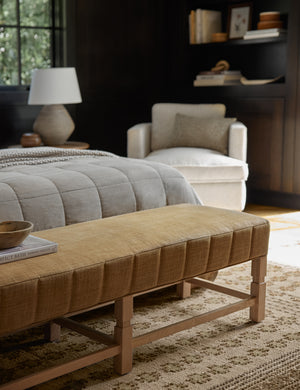 The Ambleside camel linen bench sits atop a patterned rug in a room with accented black wooden walls and a natural linen bed
