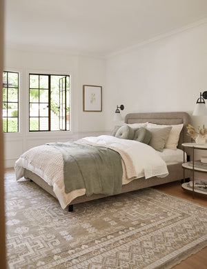Gwendolyn Pebble Linen Platform Bed sits in a bedroom with olive, natural, and white linens atop a brown and cream patterned rug