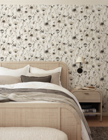 #color::brown | The Scalamandre Lo soft and pastoral brown toned floral wallpaper is in a bedroom with a cane and woven framed bed, gray toned bedding, and a whitewashed wooden nightstand