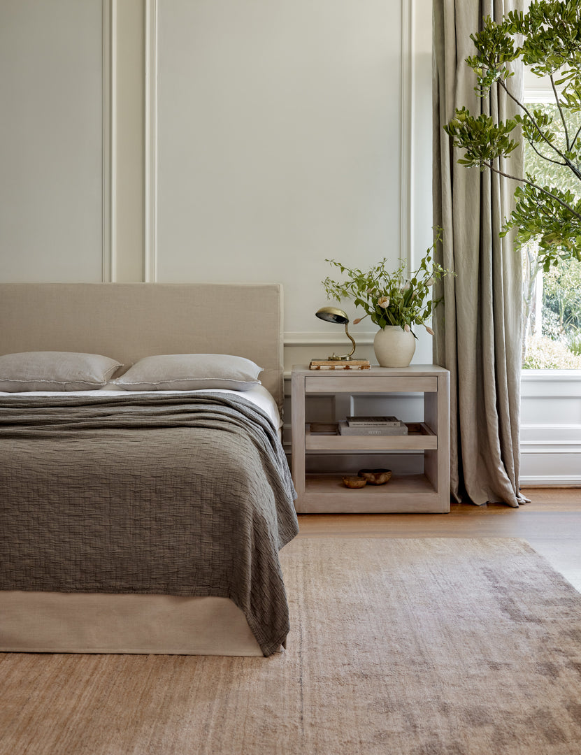 #color::pebble #size::king #size::queen #size::twin | The Ojaj pebble cotton matelassé coverlet by pom pom at home lays atop a gray linen framed bed in a bedroom with a gray plush rug and a white washed wooden nightstand