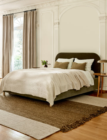 #showall::40145434214499 | The Solene Loden Velvet platform bed sits atop a brown and natural rug in a room with a tall ceiling and accented walls