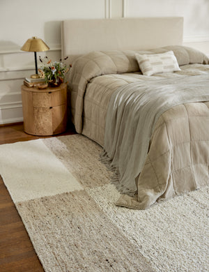 The Woburn Rug lays in an ivory bedroom with tall windows under a neutral linen framed bed