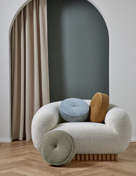 #color::canyon-blue | The Velvet Disc Pillow by Sarah Sherman Samuel in canyon blue, amber, and juniper green sit atop a boucle accent chair