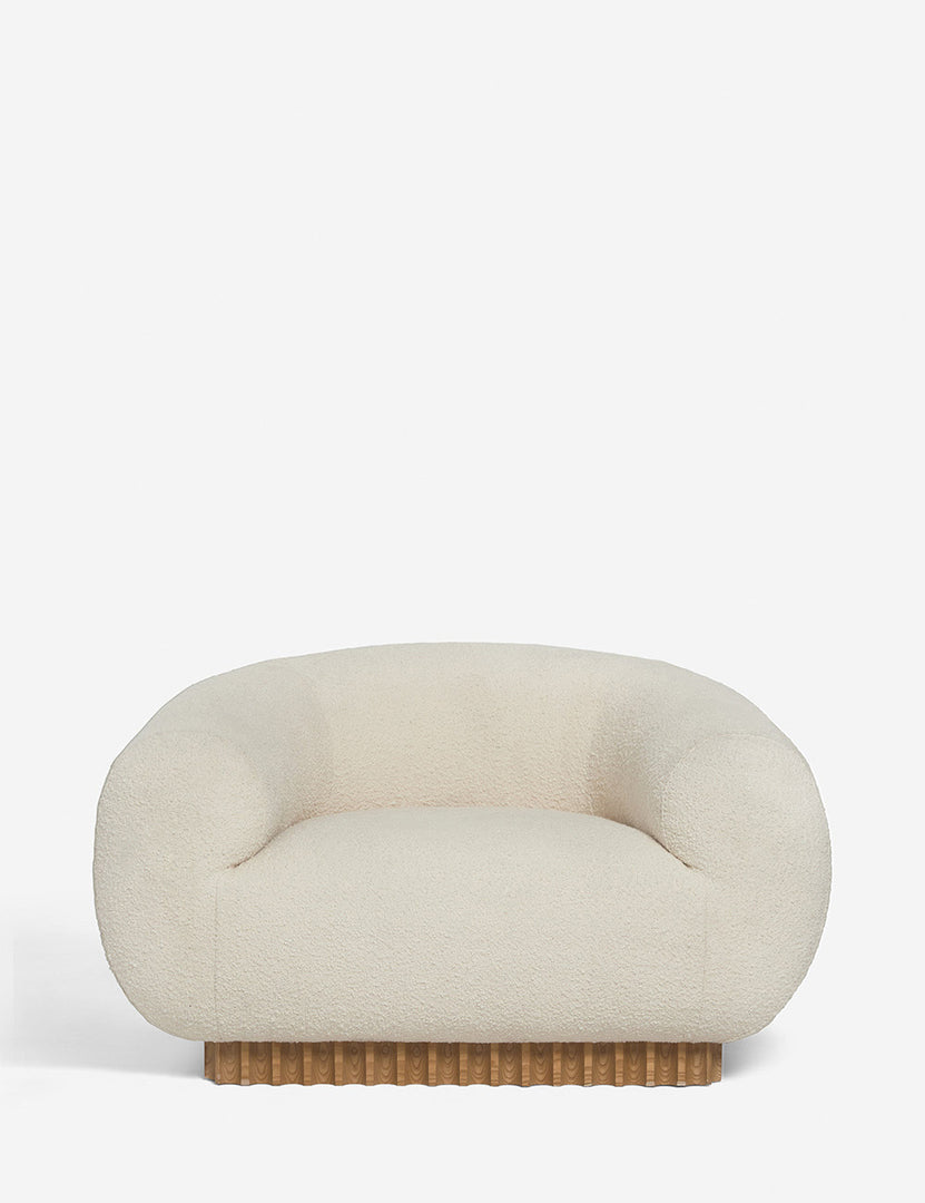 | Billow ivory boucle upholstered rounded lounge chair with a rippled wooden plinth base by Sarah Sherman Samuel