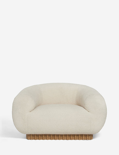 | Billow ivory boucle upholstered rounded lounge chair with a rippled wooden plinth base by Sarah Sherman Samuel