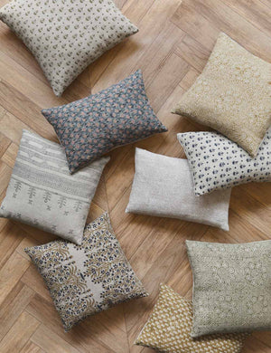 Tamra blue and pink lumbar pillow with floral patterns lay on a chevron wooden floor with other floral pillows