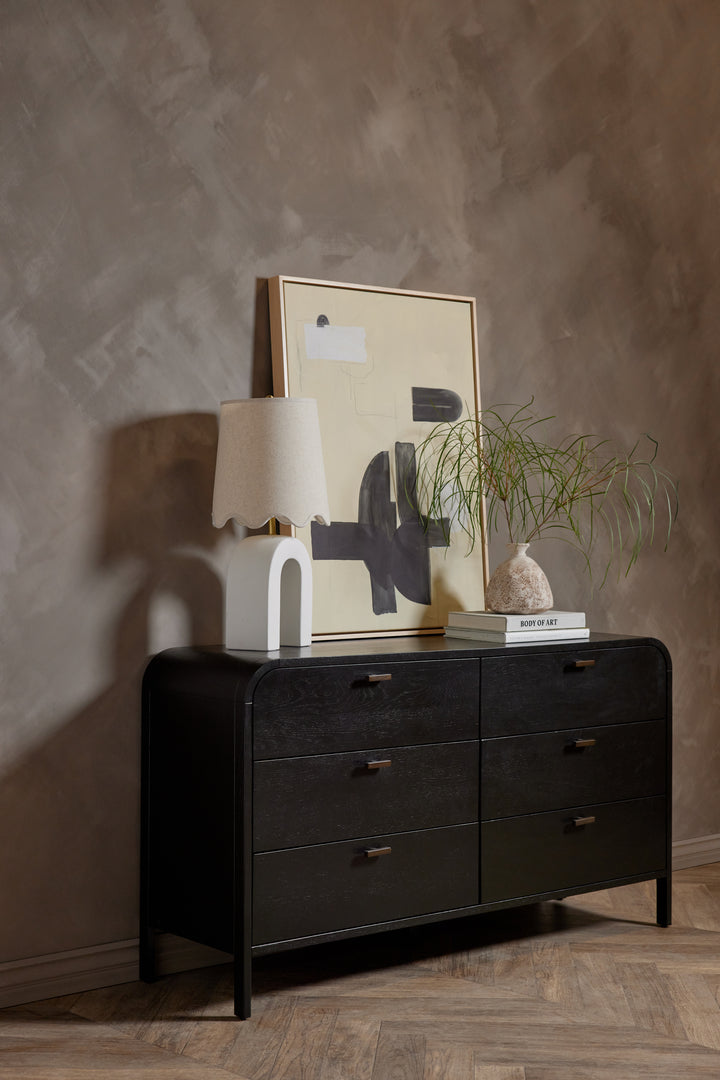 #color::black | The the brooke black oak 6-drawer rounded dresser sits in a room with a sculptural lamp and wall art atop it