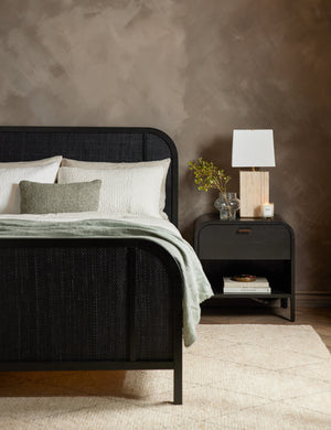 The Brooke one drawer black nightstand sits next to the Brooke platform bed behind a diamond patterned ivory rug
