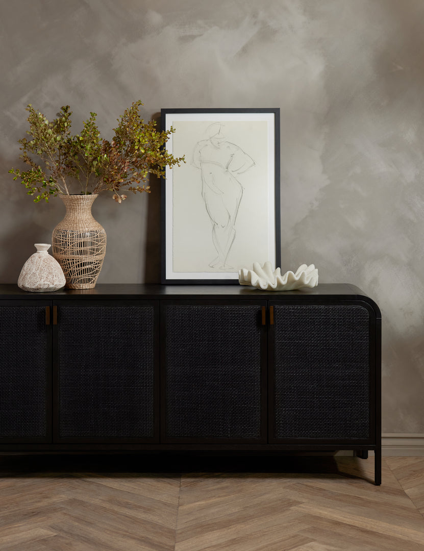 #color::black | The Brooke black solid oak sideboard sits against a gray wall with a woven vase, ruffle bowl, and portrait wall art sitting atop it