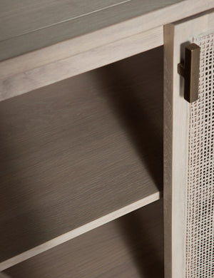 Close-up of the iron pull and an open rattan door on the Brooke natural solid oak sideboard