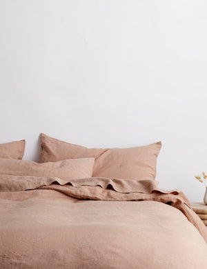 The European Flax Linen fawn pink Duvet Cover by Cultiver lays on a bed with other cultiver linens
