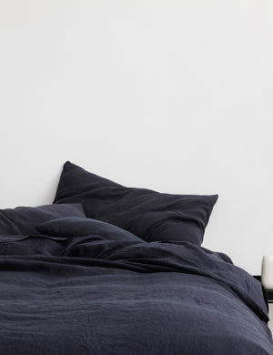 The European Flax Linen navy Duvet Cover by Cultiver lays on a bed with other cultiver linens