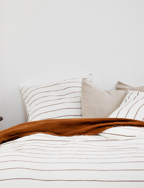 #color::cedar-stripe #size::queen #size::king | The European Flax Linen cedar orange stripe Duvet Cover by Cultiver lays on a bed with other cultiver linens