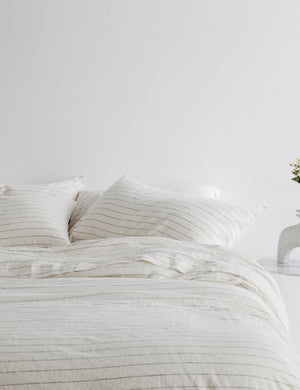 The European Flax Linen pencil stripe Duvet Cover by Cultiver lays on a bed with other cultiver linens