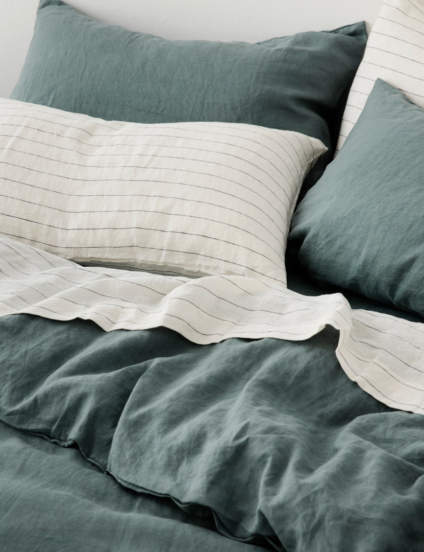 #color::bluestone #size::king #size::standard | The set of two european flax linen bluestone pillowcases by cultiver lay on a bed with pencil stripe linens by cultiver