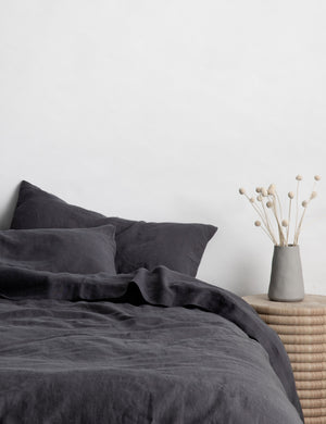 The European Flax Linen slate gray Duvet Cover by Cultiver lays on a bed with other cultiver linens