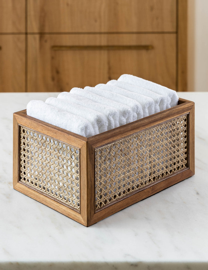 | Rattan cane bin by NEAT Method sits on a marble countertop with white towels