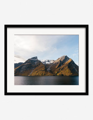 Fjords Photography Print in a black frame featuring crisp mountain peaks emerging from the dark sea into a clear, cool light by Carley Rudd