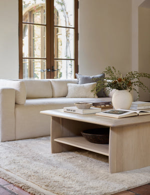 Cedro large minimalist light wood coffee table with shelf styled in a living room with an ivory sofa and fringe rug.