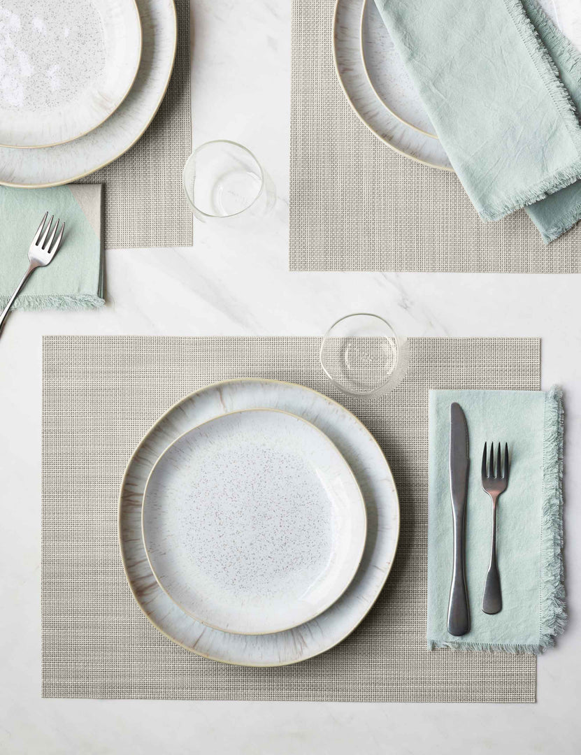 #color::parchment | The Set of four parchment-toned Mini Basketweave Rectangle Placemat by Chilewich sits under a white dinnerware set