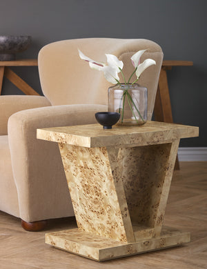Chloe Burl Wood Side Table sits next to a beige velvet accent chair with a small black bowl and glass vase sitting atop it