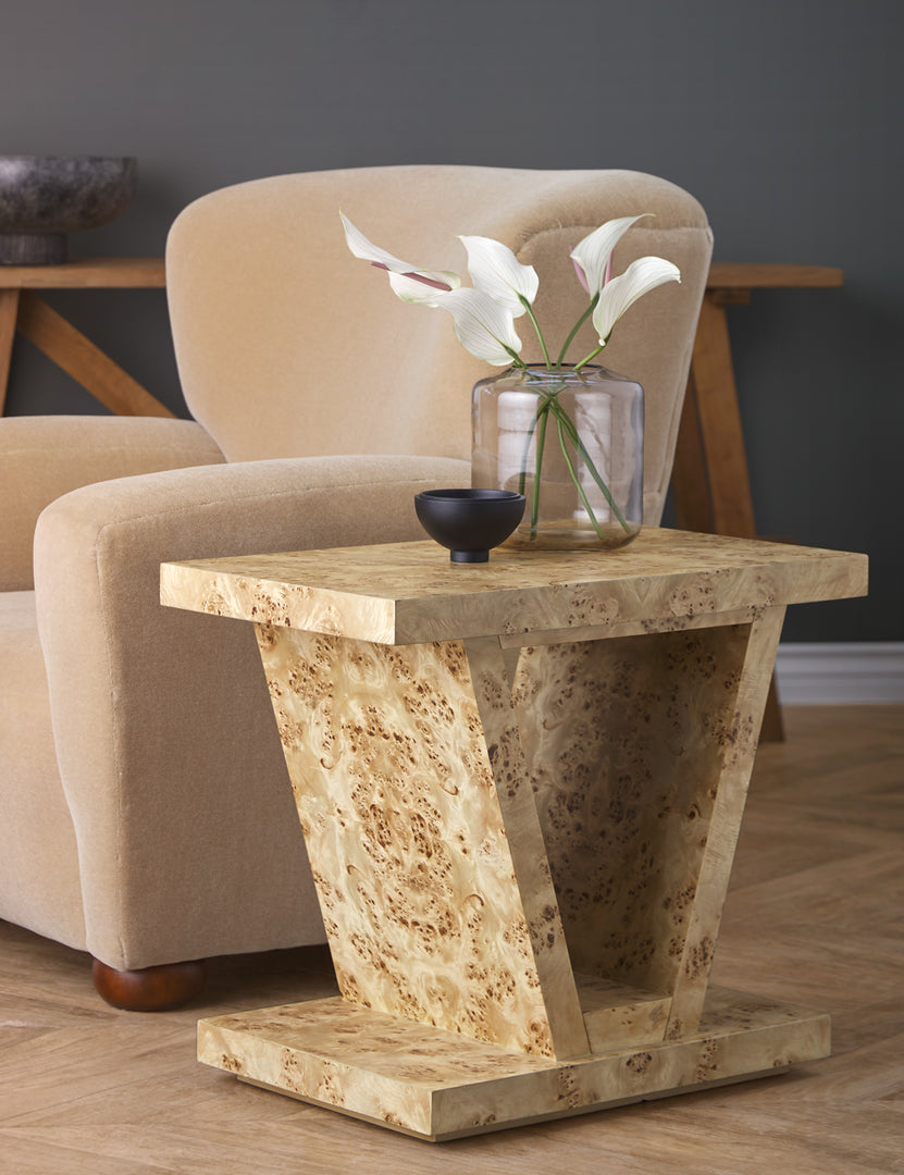 | Chloe Burl Wood Side Table sits next to a beige velvet accent chair with a small black bowl and glass vase sitting atop it
