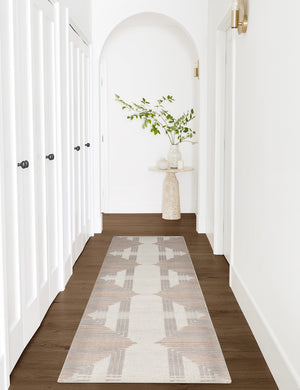 The Colette Rug in its runner size lays in a white arched hallway with a natural side table at the end