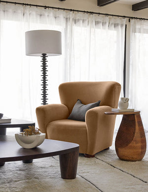 The Avery Bronze Mohair accent chair sits atop a plus ivory rug next to a sculptural floor lamp and side table