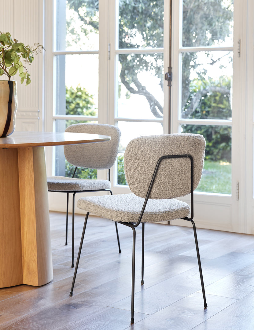  | Two of the Hayes Dining Chairs sit around a natural wooden dining table in a dining room with white walls and french doors 