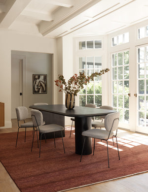 Six of the Hayes Dining Chairs sit around a black rectangular dining table atop a burgundy rug in a room with french doors