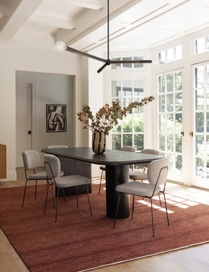 The Heritage brick rugs lays in a dining room with a black dining table and six dining ivory sherpa dining chairs