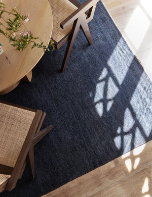 The Heritage indigo rug lays under a round dining table with rattan dining chairs