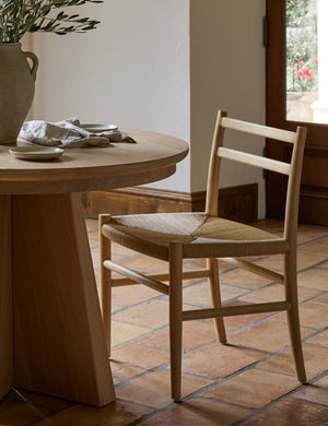 Nicholson slim natural oak wood frame and woven seat dining chair styled with a round dining table.