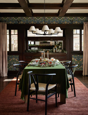 The Heritage brick rug lays in a festive dining room with green patterned wallpaper and a dining table with green linens