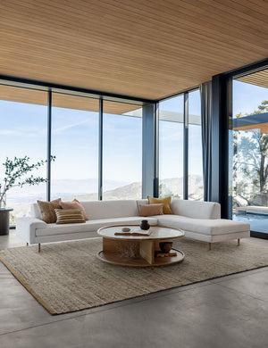 The Khloe gray rug lays in a living room with wrap around floor to ceiling windows under an ivory sofa