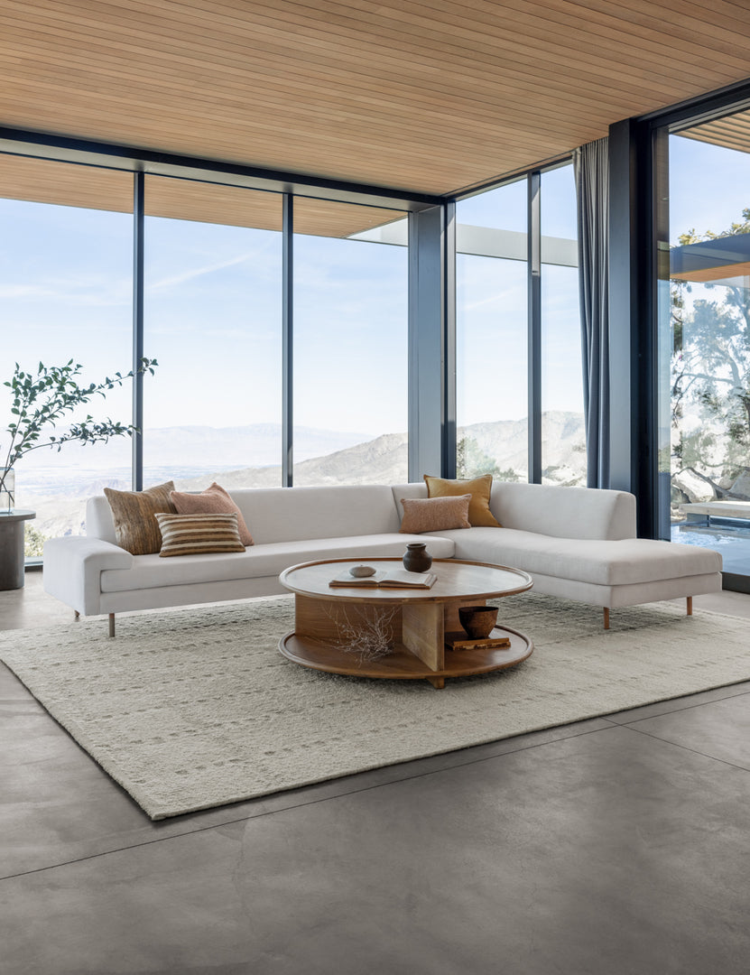 #color::white #configuration::right-facing | The Estee white linen right-Facing Sectional Sofa sits atop a textured white rug in a room with floor to ceiling windows