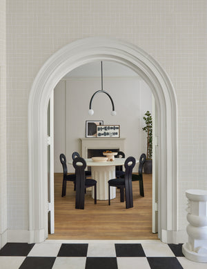 The Irregular Grid Wallpaper is in a room with an arched entryway into a dining room with a round dining table