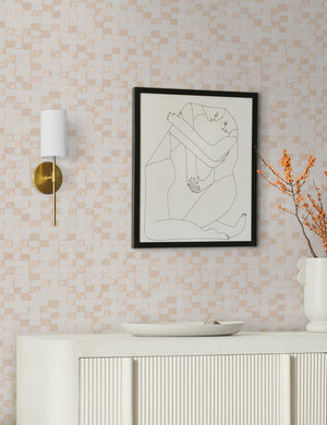 Taupe and ivory Checkerboard Wallpaper by Sarah Sherman Samuel is in a room with a white console table and an abstract wall art of two people