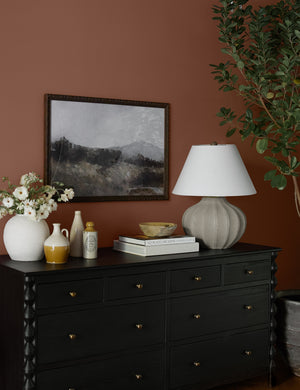 The Hillside Print hangs on a terracotta-toned wall above a black sideboard with sculptural legs