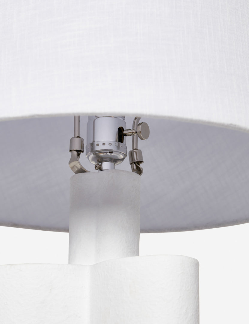 #color::white | The silver hardware and light switch on the inside of the Duffy white table lamp 