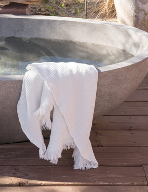 The Sherra white Waffle Towel by House No. 23 is hung at the edge of a stone outdoor bath