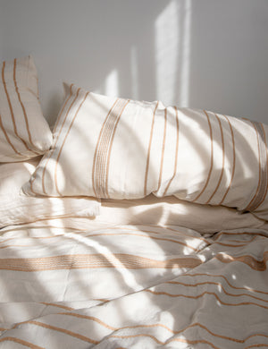 The Marlo Cotton hand loomed beige striped Duvet Set by House No. 23 lays on a bed in a sunny bedroom