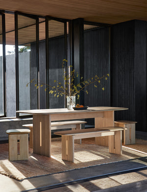 The Henrik light wood bench sits on both sides of a dining room table in a room with black-wooden walls